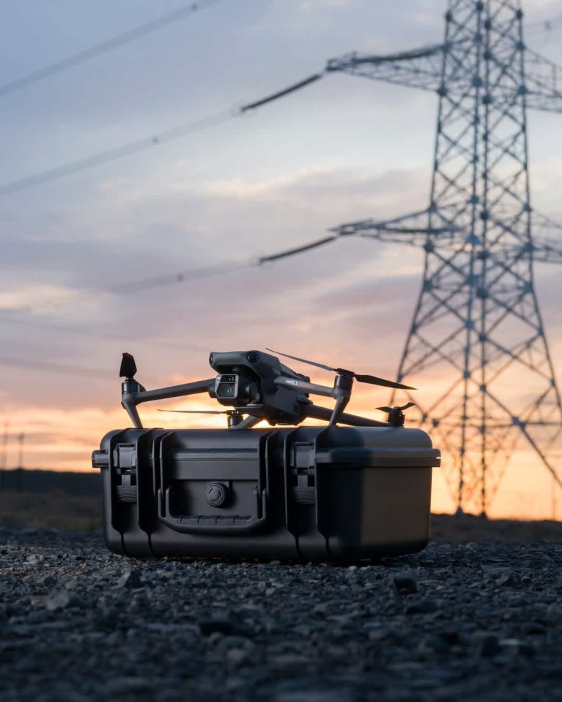 Survey drone positioned on equipment case near electricity pylon for utility corridor aerial survey in the UK